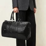 Diamond quilted duffel bag carried by top soft handles showing compact hand-carry mode for gym and travel